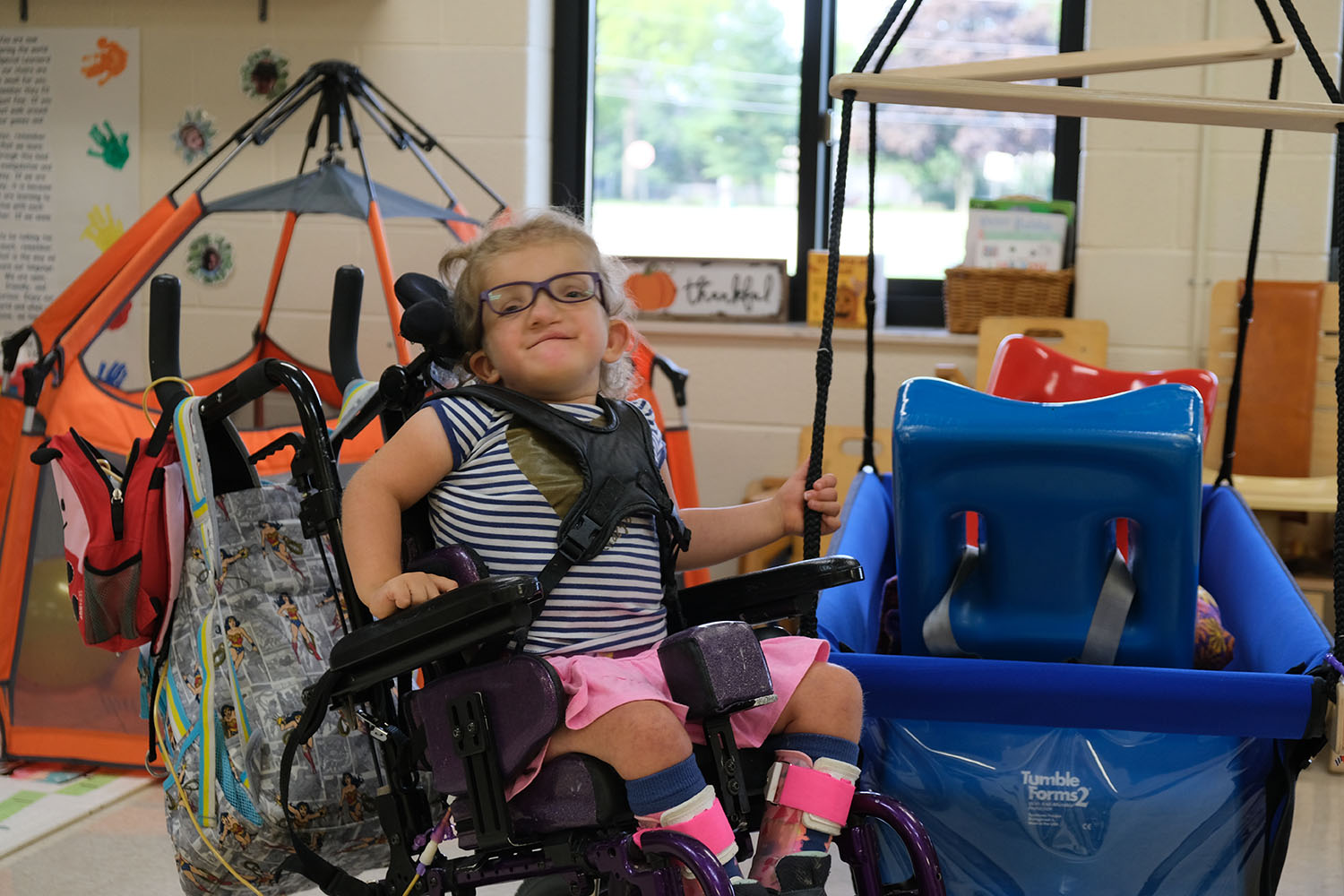 Girl in wheelchair with backpack smiling